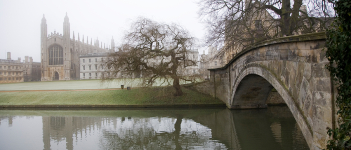 A foggy day at Cambridge showing a bridge over a canal and a castle like building in the background